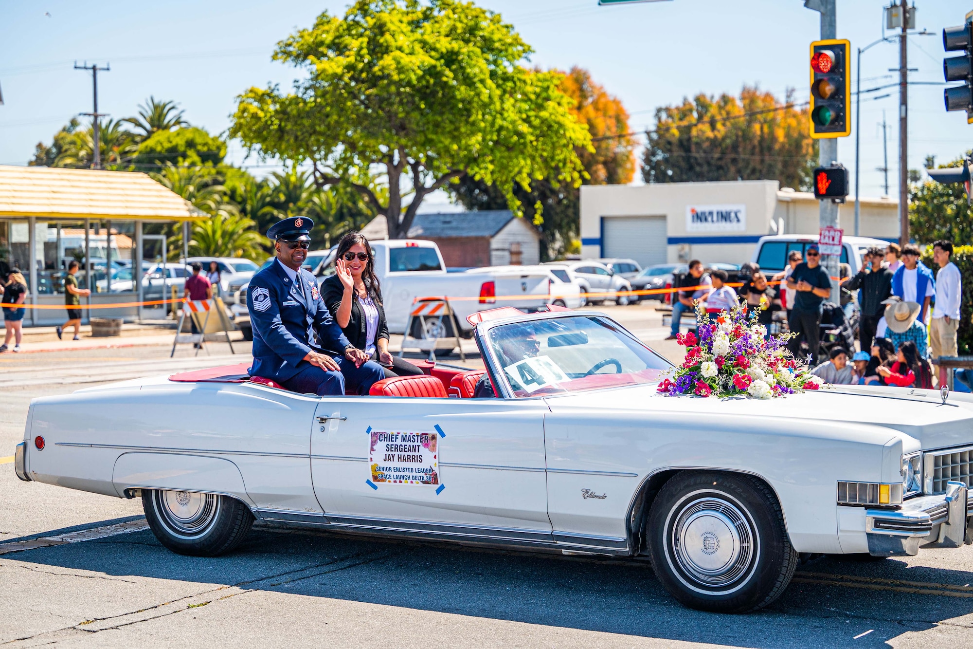 U.S. Space Force Chief Master Sgt. Jay L. Harris, Space Launch Delta 30 command senior enlisted leader, and his wife ride in the back of a convertible car during the Lompoc Flower Festival Parade.