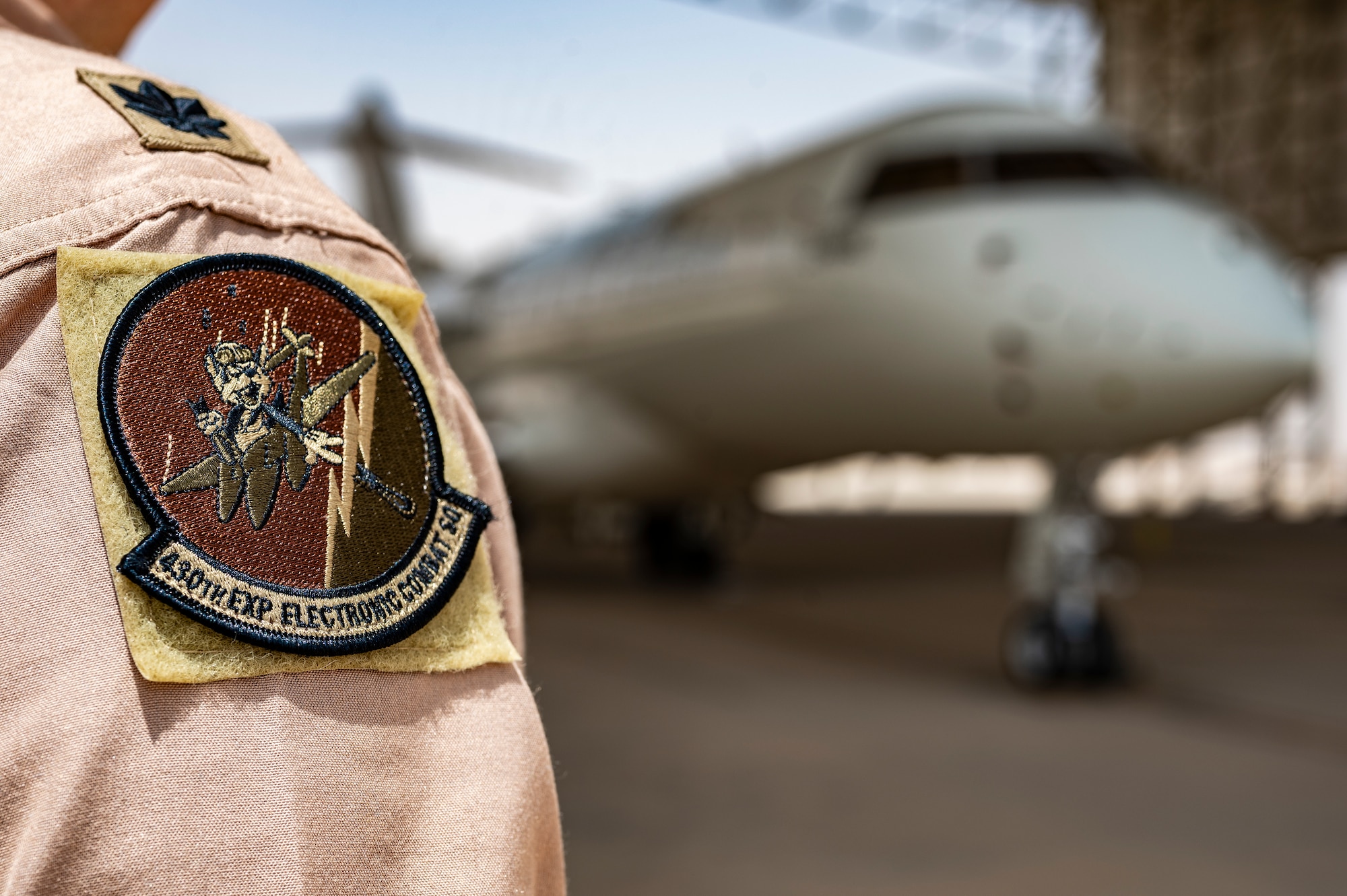 A U.S. Air Force E-11A Aircraft pilot assigned to the 430th Expeditionary Electronic Combat Squadron poses for a photo at an undisclosed location within the U.S. Central Command area of responsibility, May 8, 2024. By consolidating critical data from various sources, the E-11 ensures seamless coordination among different aircraft, even when line-of-sight communication is limited. (U.S. Air Force photo)