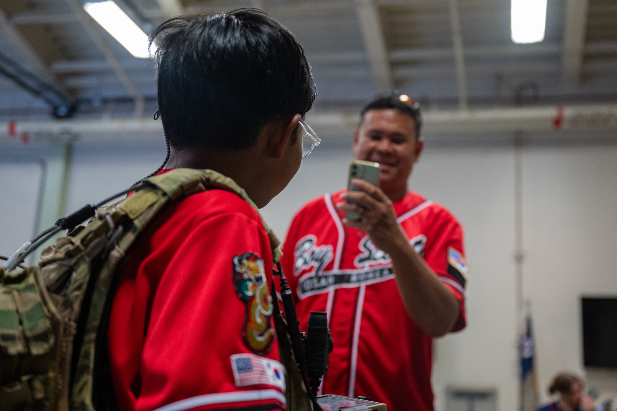 U.S. Air Force Master Sgt. Ryan Padilla, American Forces Network branch chief for technical services, takes a photograph of his son wearing a joint terminal attack controller tactical vest during a youth aviation day at Osan Air Base, Republic of Korea, June 15, 2024. The event allowed members of the community, Civil Air Patrol Squadron NHQ-127, Scouts BSA and the Osan City Korea Scout Association to interact with service members at Osan AB. (U.S. Air Force photo by Airman 1st Class Chase Verzaal)