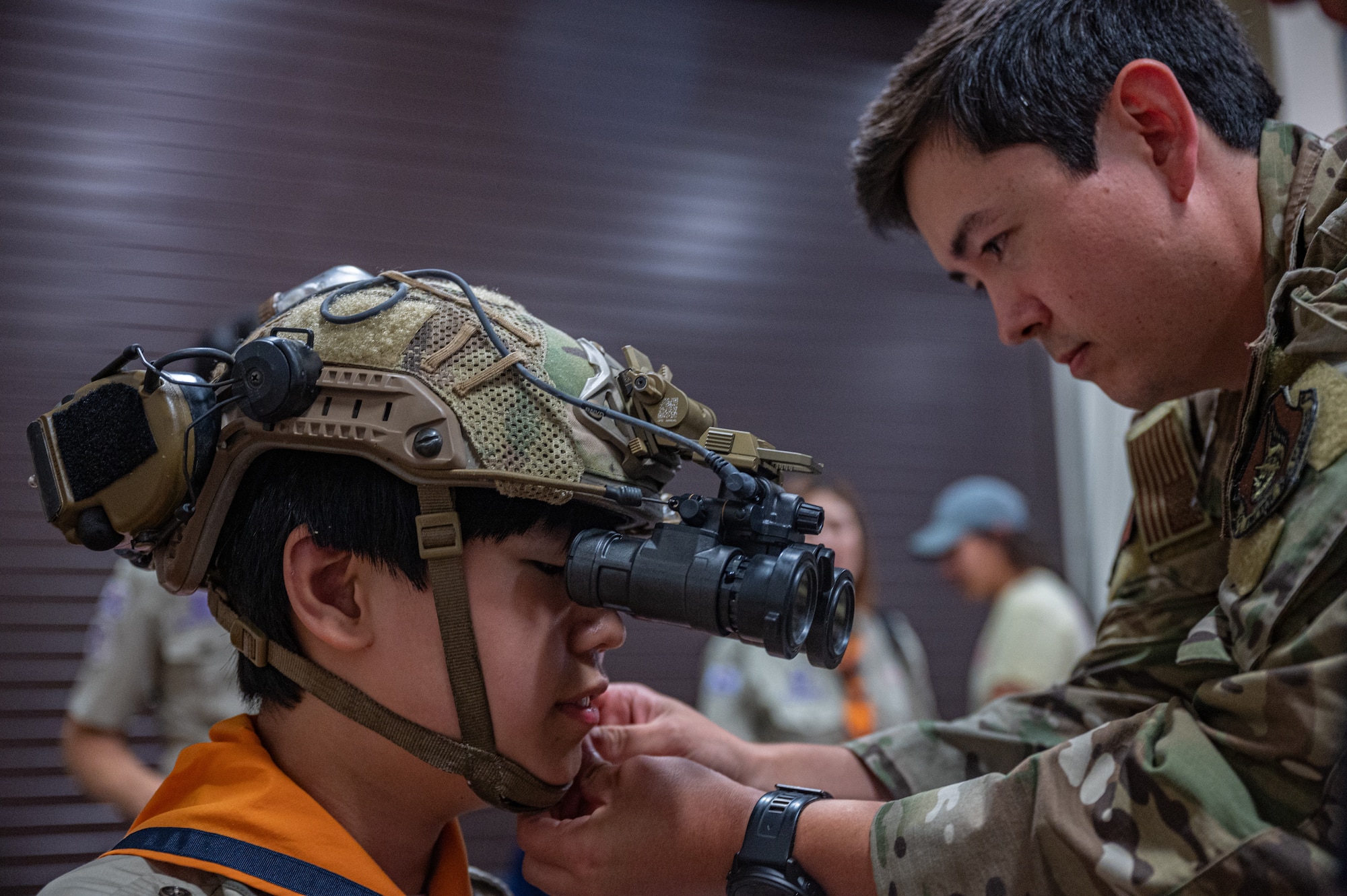U.S. Air Force Senior Airman Kai Wakeland, 607th Air Support Operations Group joint terminal attack controller, fastens a tactical helmet onto a member of the Osan City Korea Scout Association during a youth aviation day at Osan Air Base, Republic of Korea, June 15, 2024. Wakeland volunteered to be a part of the panel of service members who welcomed the participant’s passion for aviation. (U.S. Air Force photo by Airman 1st Class Chase Verzaal)