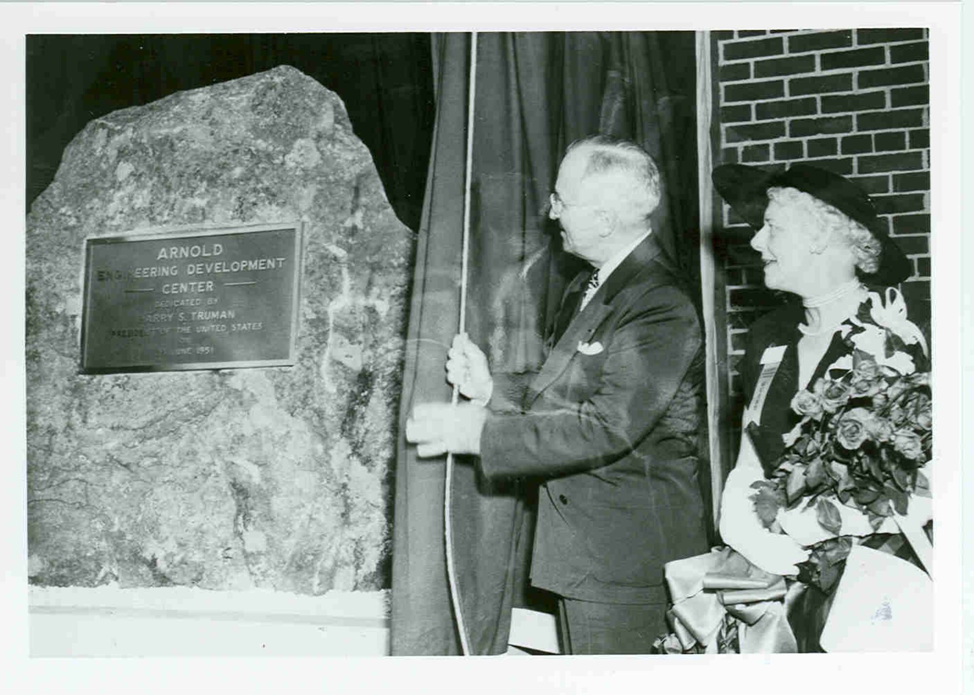 During a June 25, 1951, ceremony at Arnold Air Force Base, Tenn., President Harry Truman draws aside the curtain to reveal a dedicatory plaque mounted to a granite rock. The ceremony was held to dedicate the Air Engineering Development Center as the Arnold Engineering Development Center in honor of Gen. Henry H. “Hap” Arnold. Pictured with Truman is Arnold’s widow, Bee. (U.S. Air Force photo)