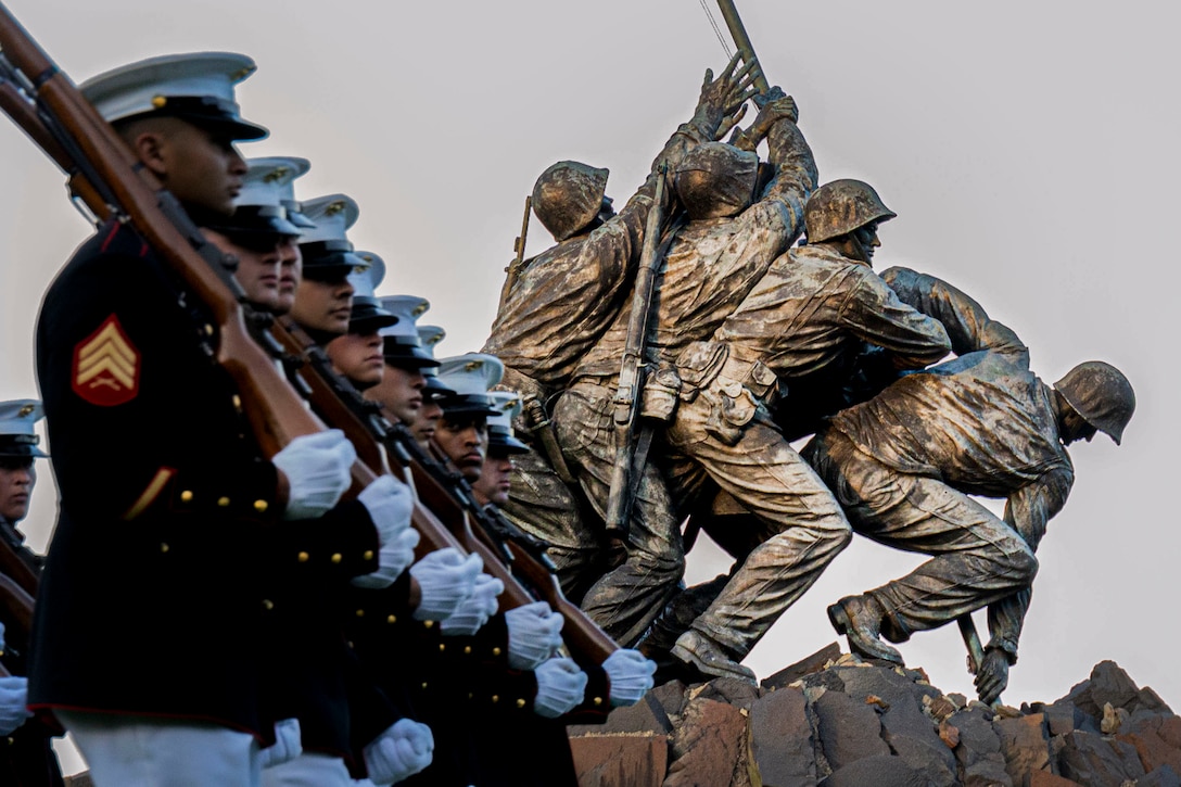 Marines move in formation in front of the Iwo Jima memorial during a sunset parade.