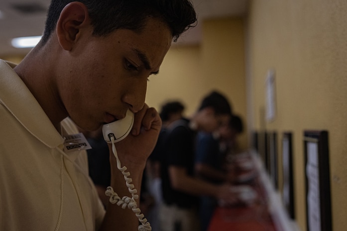 A new U.S. Marine Corps recruit with Charlie Company, 1st Recruit Training Battalion, makes a phone call home as part of a receiving event at Marine Corps Recruit Depot San Diego, California, June 17, 2024. During the receiving process, recruits are checked for contraband, given a haircut, make a scripted phone call home, and issued their gear required for training. (U.S. Marine Corps photo by Lance Cpl. Jacob B. Hutchinson)