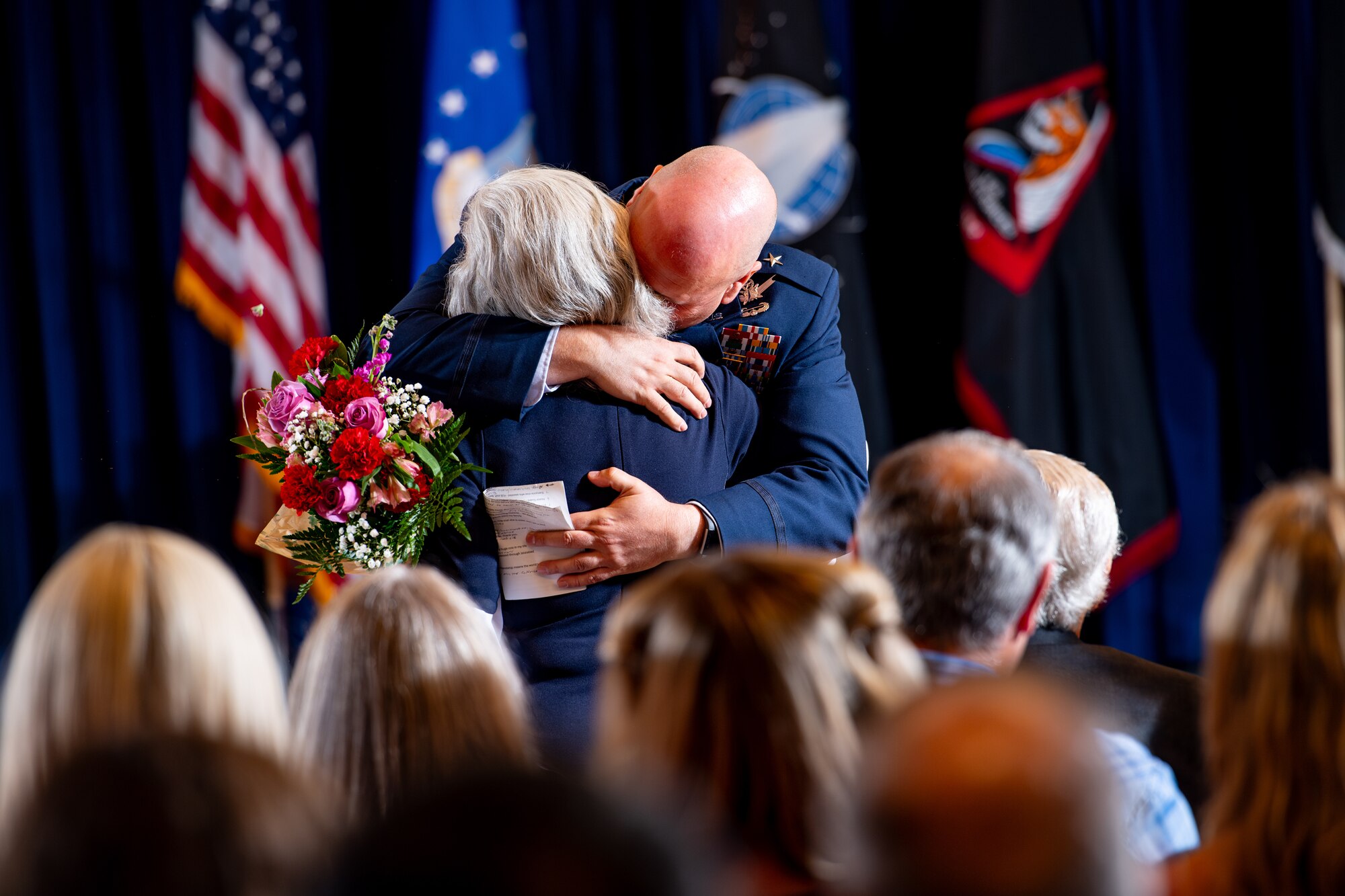 Man in uniform hugs mother with flowers