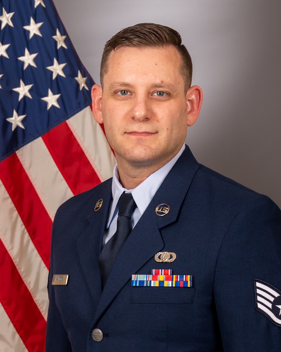 Official photo of Staff Sergeant Jason Hammers with American flag over right shoulder