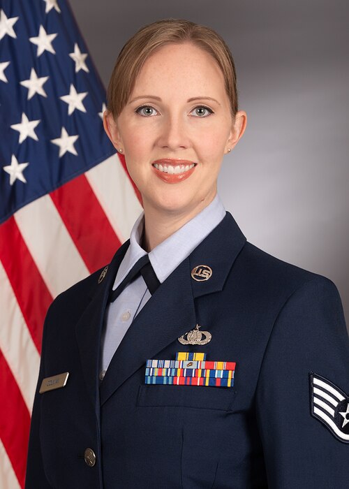 Official photo of Staff Sergeant Rachael Colman with American flag over right shoulder
