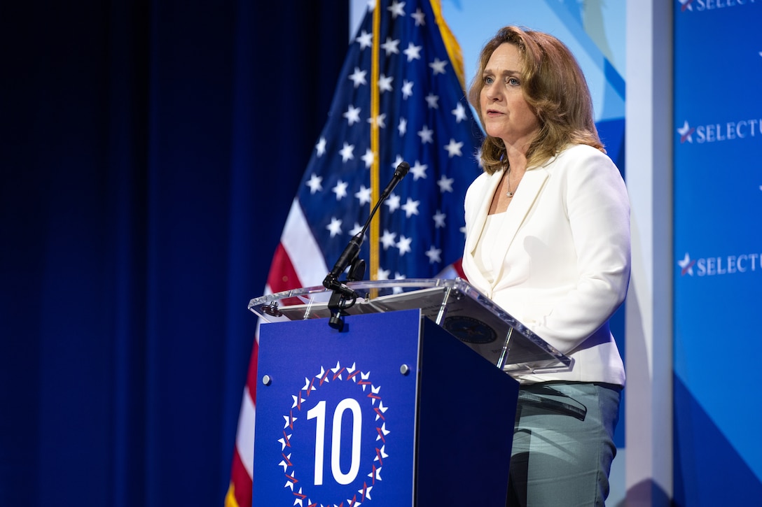 Deputy Defense Secretary Kathleen Hicks speaks at a lectern with a U.S. flag behind her.