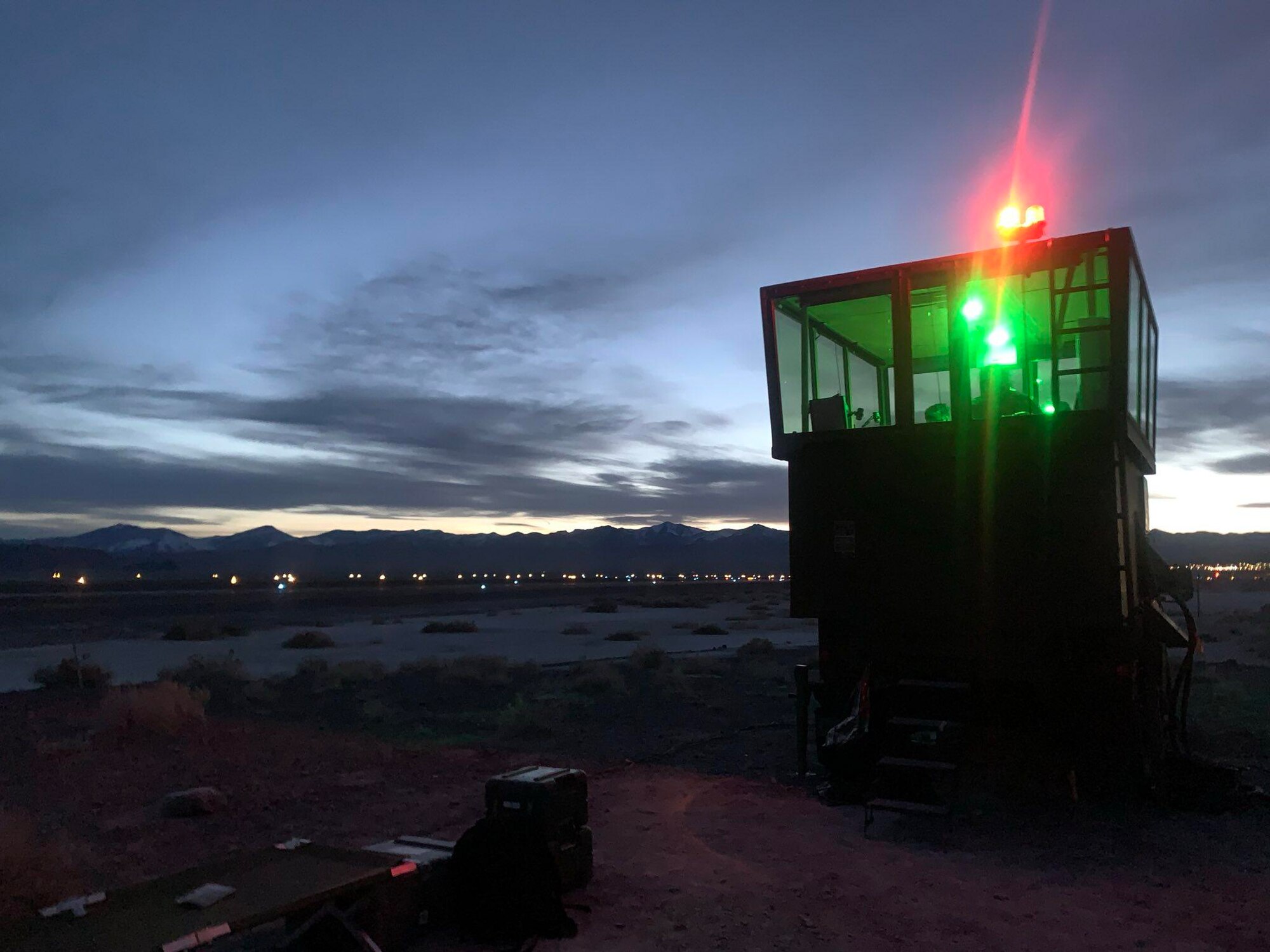 Red and green lights from a mobile air traffic control tower glow on the airfield.