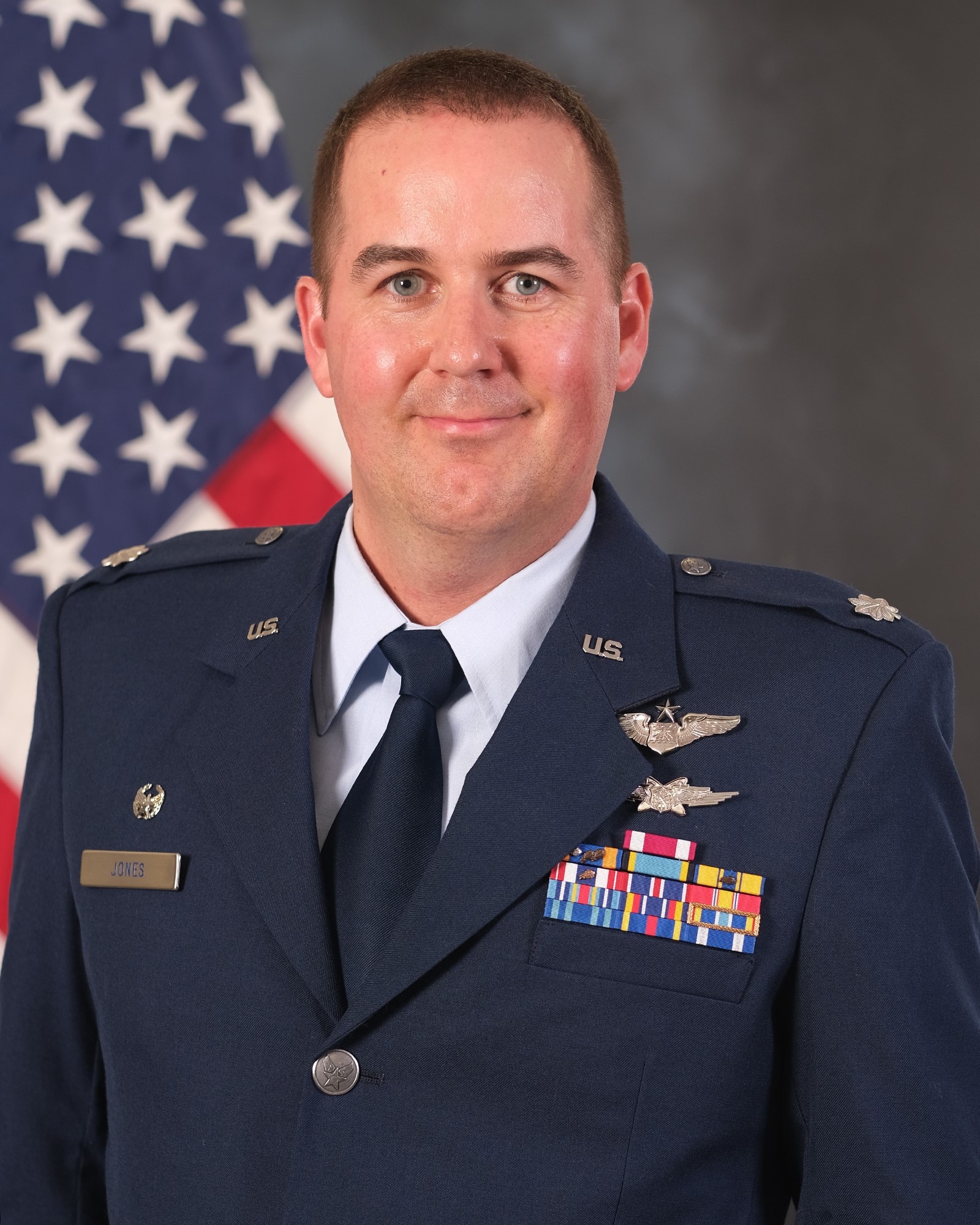 photo of uniformed U.S. Air Force Airman standing in front of U.S. flag.