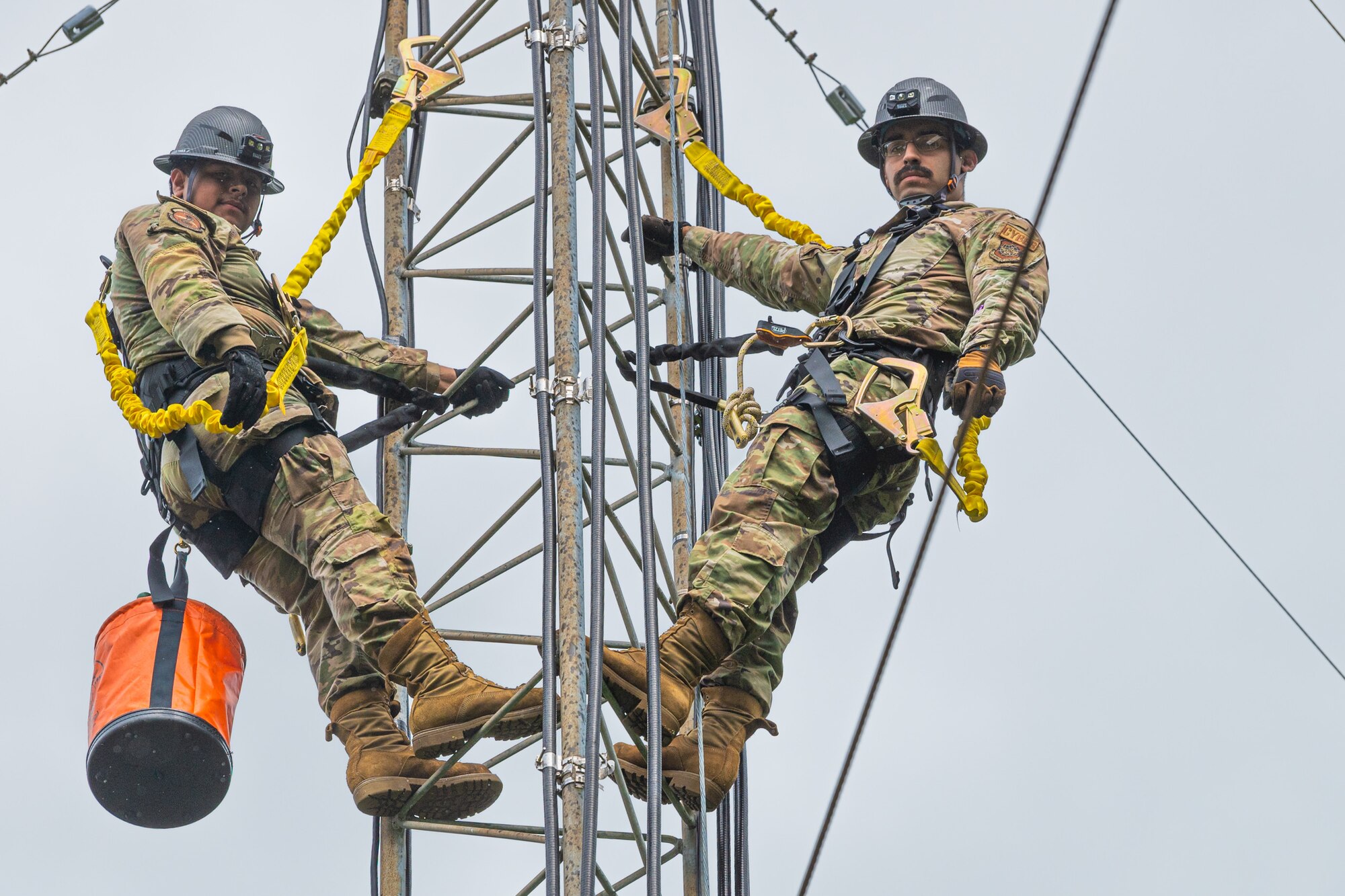 U.S. Air Force Senior Airman Angel Cortez, left, and Senior Airman Hector Salinas, both cable and antenna systems technicians with the 627th Communications Squadron, climb an antenna tower at Joint Base Lewis-McChord, Washington, May 28, 2024. Cable and antenna systems Airmen work closely to ensure safety procedures are met and assist each other during operations. (U.S. Air Force photo by Airman 1st Class Benjamin Riddle)
