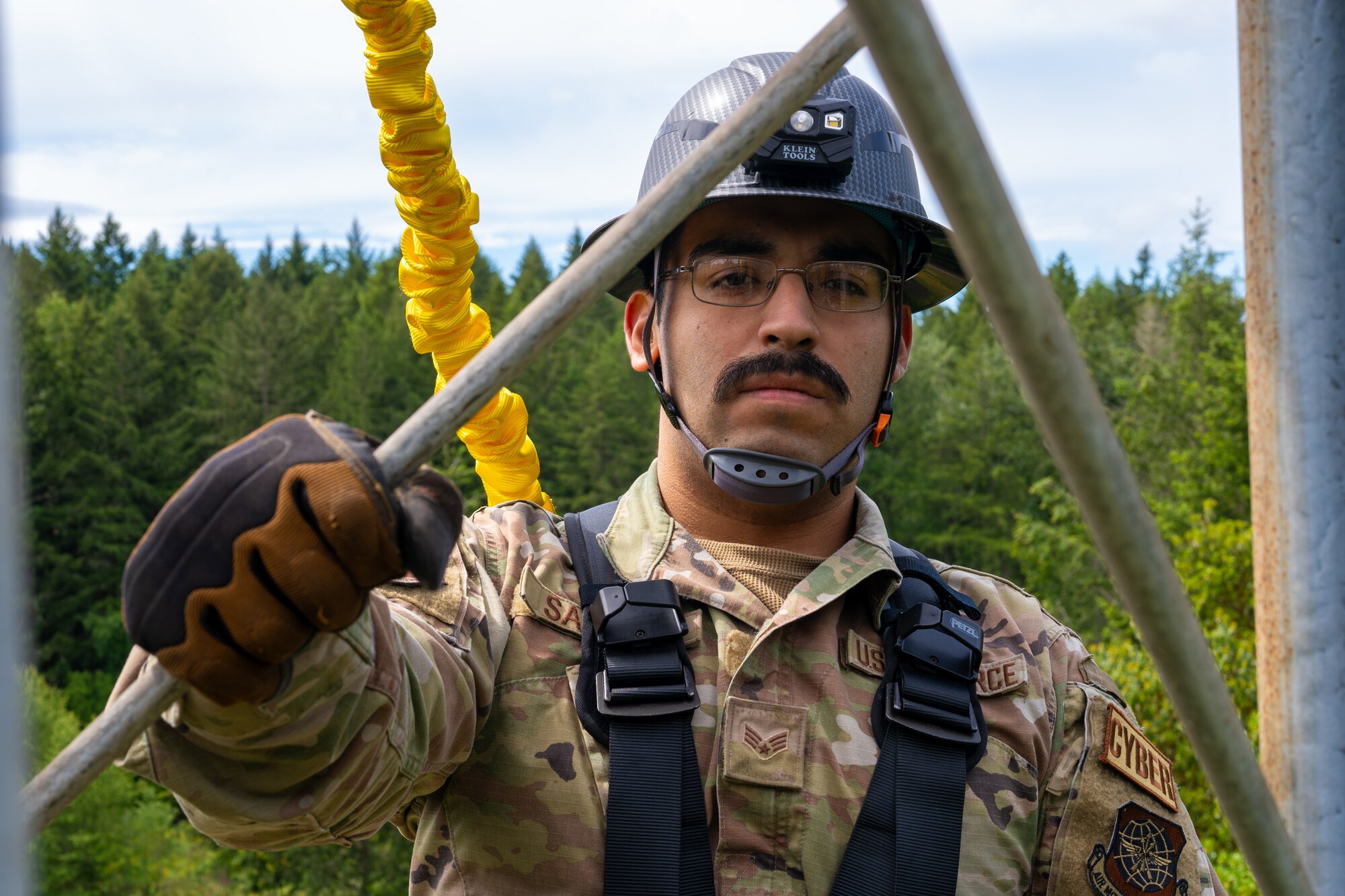 U.S. Air Force Senior Airman Hector Salinas, a cable and antenna systems technician with the 627th Communications Squadron, suspends off of an antenna tower at Joint Base Lewis-McChord, Washington, May 28, 2024. Cable and antenna systems Airmen are required to take safety precautions while working in the field.  (U.S. Air Force photo by Airman 1st Class Benjamin Riddle)