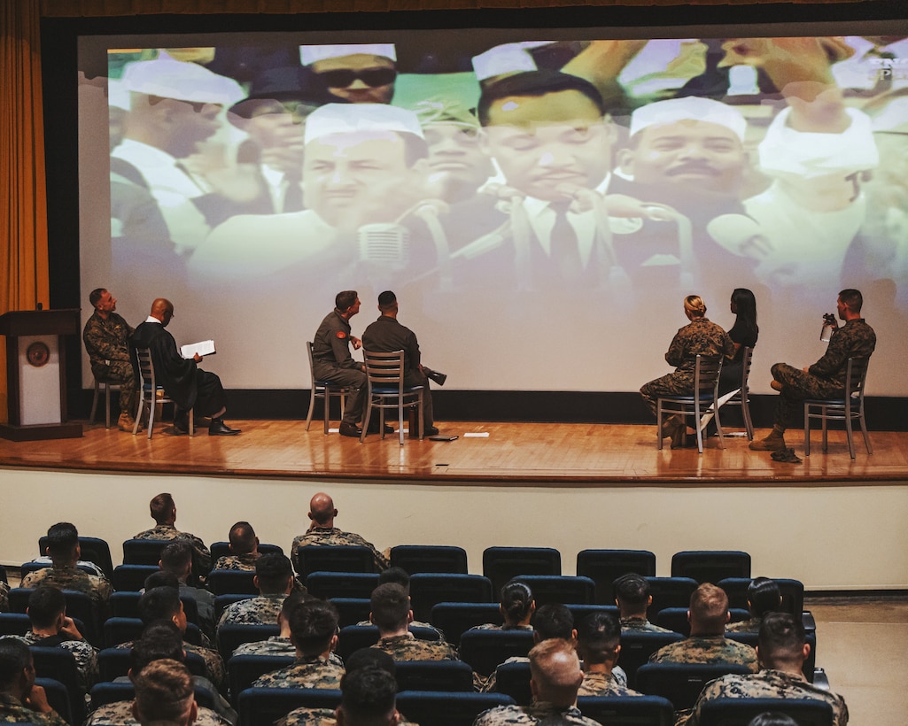 U.S. Marines and base residents with Marine Corps Air Station Futenma watch a video during a Dr. Martin Luther King Jr. celebration on MCAS Futenma, Okinawa, Japan, Jan. 17, 2023. During the celebration, Marines learned about Dr. King and the political movements of his time through videos and songs addressing racial injustice and the hope for a better future. After taking a pledge to promote equal opportunity, the Marines linked arms and sang together, showing their unity and commitment to equality. (U.S. Marine Corps photo by Cpl. Jonathan Beauchamp)