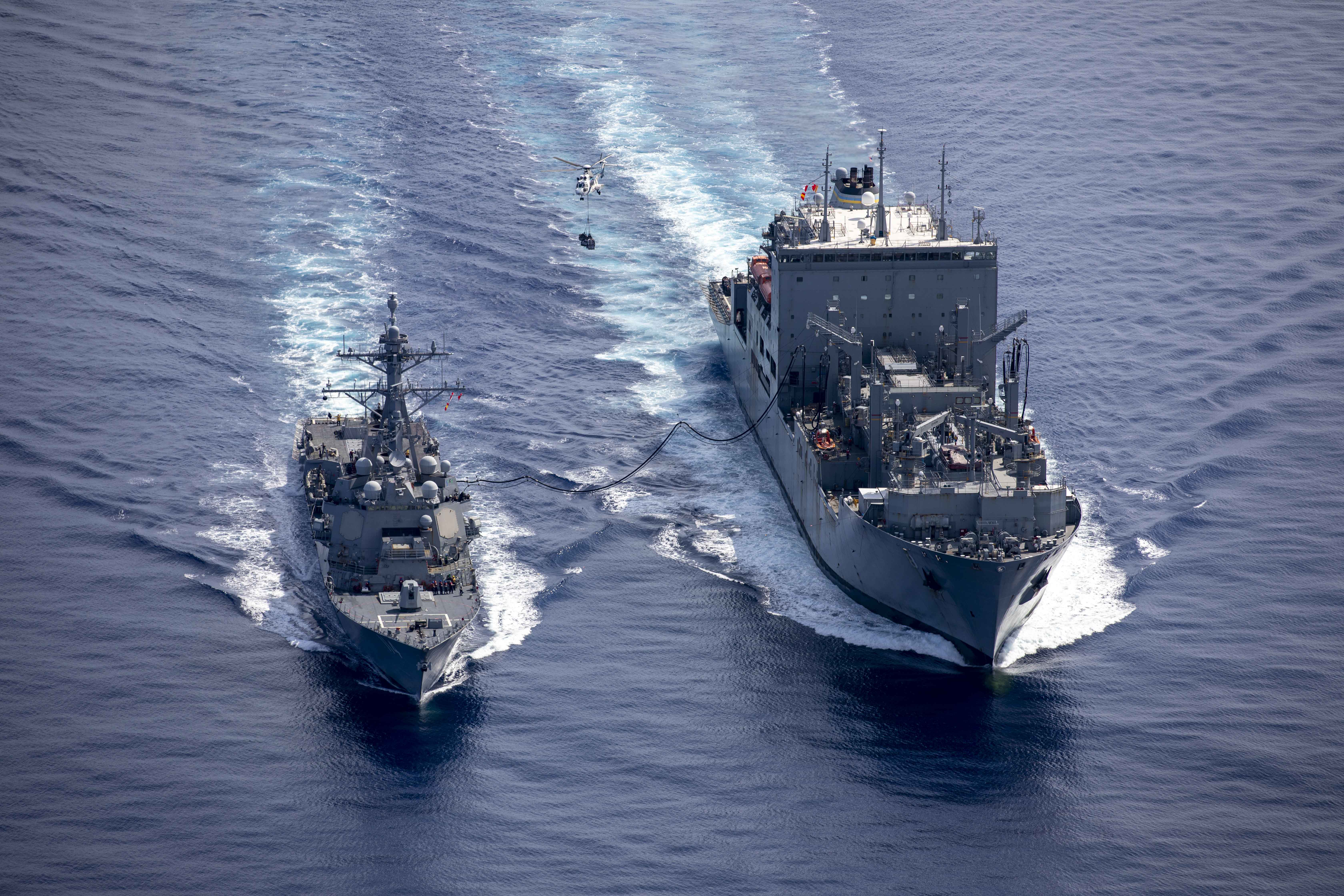 The Arleigh Burke-class guided-missile destroyer USS Ralph Johnson (DDG 114), left, conducts a replenishment-at-sea with USNS Wally Schirra (T-AKE-8), right, during bilateral operations with Royal Canadian Navy Halifax-class frigate HMCS Montreal (FFH 336) in the South China Sea, June 18, 2024.