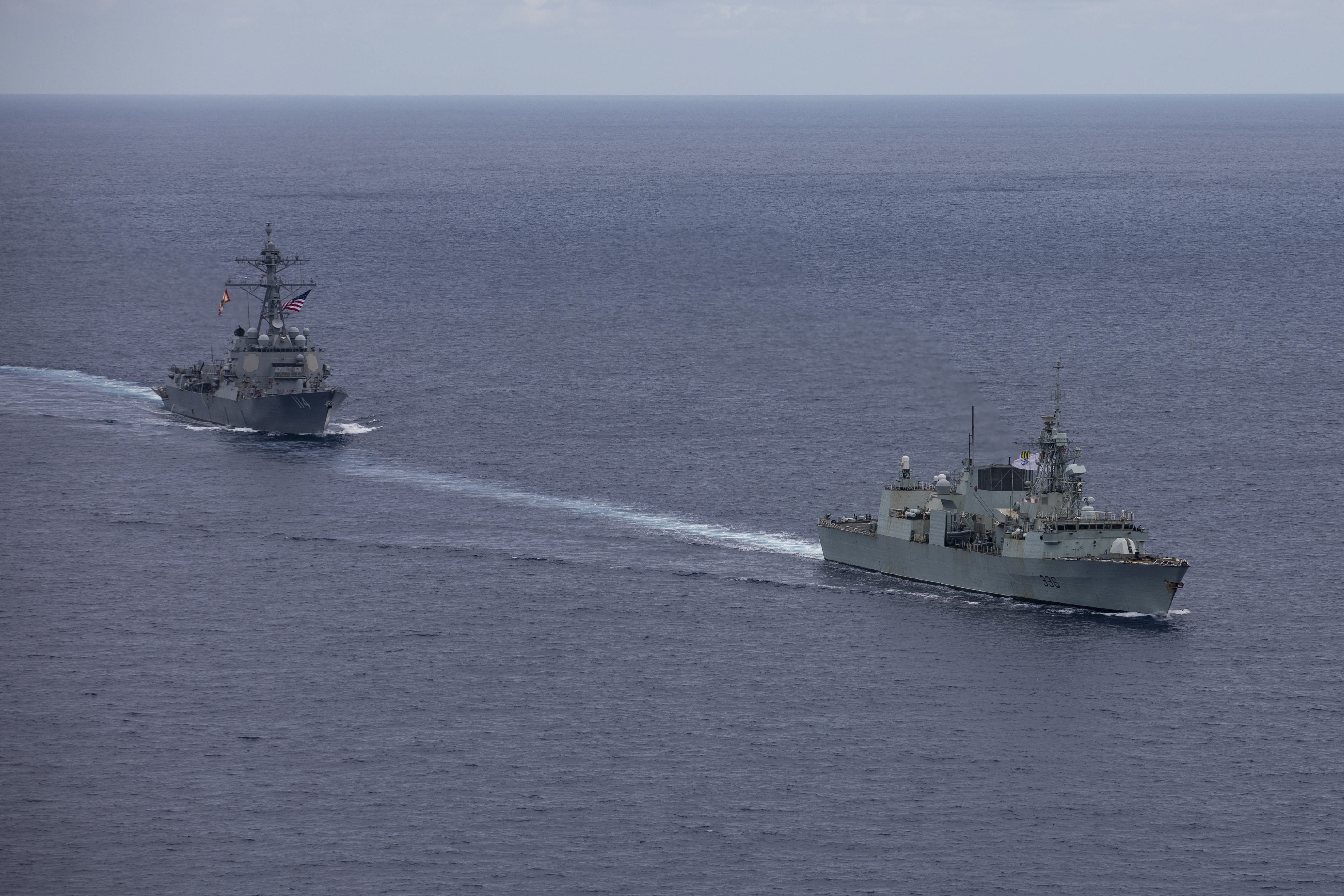 240618-N-HT008-1760 SOUTH CHINA SEA (June 18, 2024) The Arleigh Burke-class guided-missile destroyer USS Ralph Johnson (DDG 114), left, conducts bilateral operations with Royal Canadian Navy Halifax-class frigate HMCS Montreal (FFH 336) in the South China Sea, June 18, 2024. Combined operations such as this are intended to improve interoperability between allied navies and support a free and open Indo-Pacific. Ralph Johnson is forward deployed and assigned to Destroyer Squadron (DESRON) 15, the Navy’s largest DESRON and the U.S. 7th fleet’s principal surface force. (U.S. Navy photo by Mass Communication Specialist Seaman Trevor Hale)