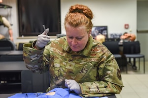 A woman practice suturing a wound on a mannequin