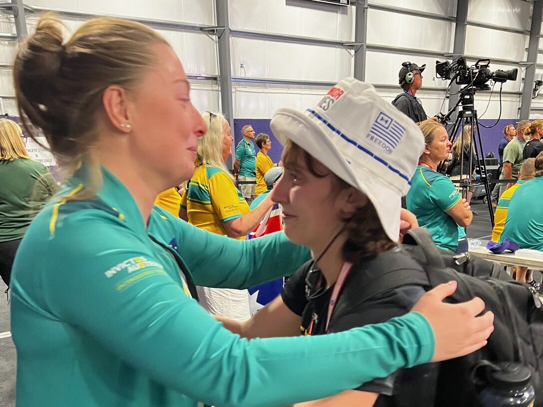 Australia Army Sgt. Emily Lahey, left, and U.S. Army Capt. Hannah Wright are brought to tears and share a hug after learning of their cancer connection at the powerlifting competition during the 2024 Department of Defense Warrior Games