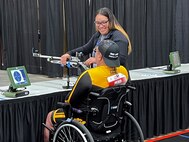 U.S. Army Sgt 1st Class Jack Peko is assisted by his wife, Gloriah Peko, in the air rifle competition during the 2024 Department of Defense Warrior Games