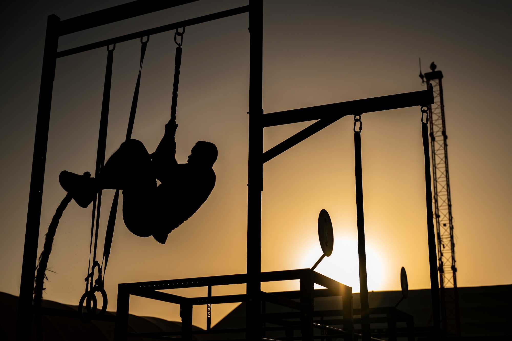 The U.S. Air Force 510th Expeditionary Fighter Generation Squadron commander climbs a rope during a CrossFit workout at an undisclosed location within the U.S. Central Command area of responsibility, June 22, 2024. During the CrossFit workout, they performed single-arm dumbbell snatches, power cleans, chest-to-bar pull-ups and rope climbs. (U.S. Air Force photo)