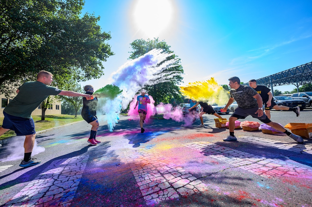 People toss colorful powder onto a runner during a Pride Month run.