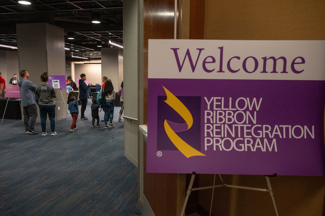 Photo of Yellow Ribbon sign and people walking in the background.