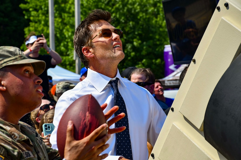 Seven time Superbowl Champion Tom Brady receives instruction on "The Impossible Kick" machine.