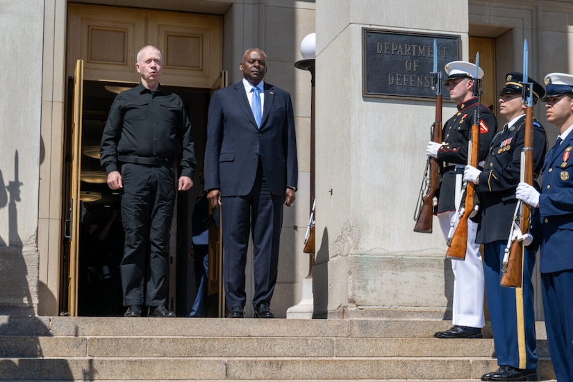 Men stand at top of steps in front of a building.