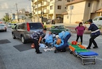 First responders provide aid to a child in a street.