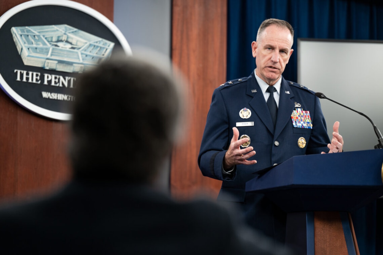 A man stands at a podium and gestures with his hands.