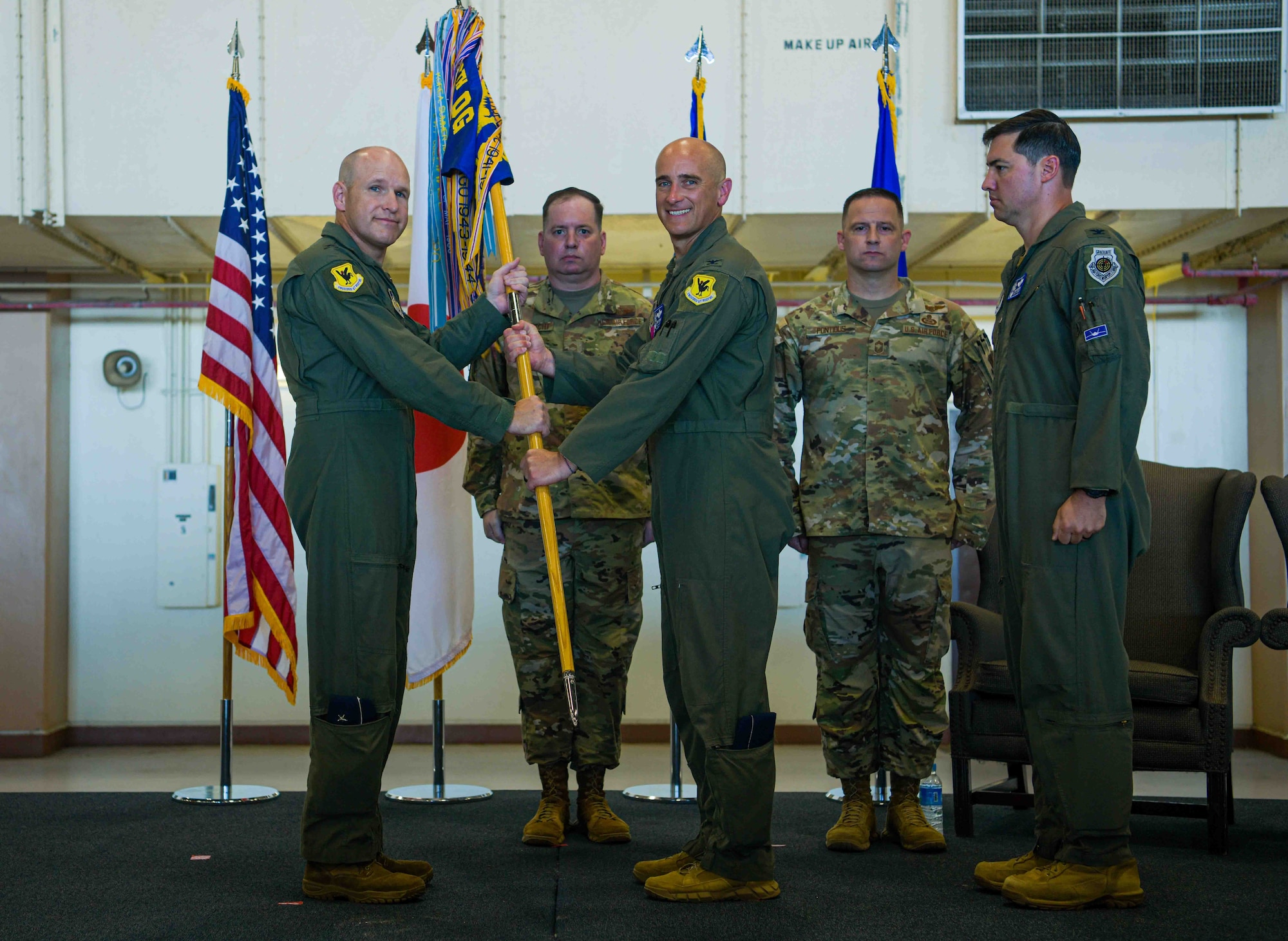 U.S. Air Force Col. Henry Schantz, right, outgoing 18th Operations Group commander, relinquishes the guidon to Brig. Gen. Nicholas Evans, left, 18th Wing commander, during the 18th OG change of command ceremony at Kadena Air Base, Japan, June 25, 2024.