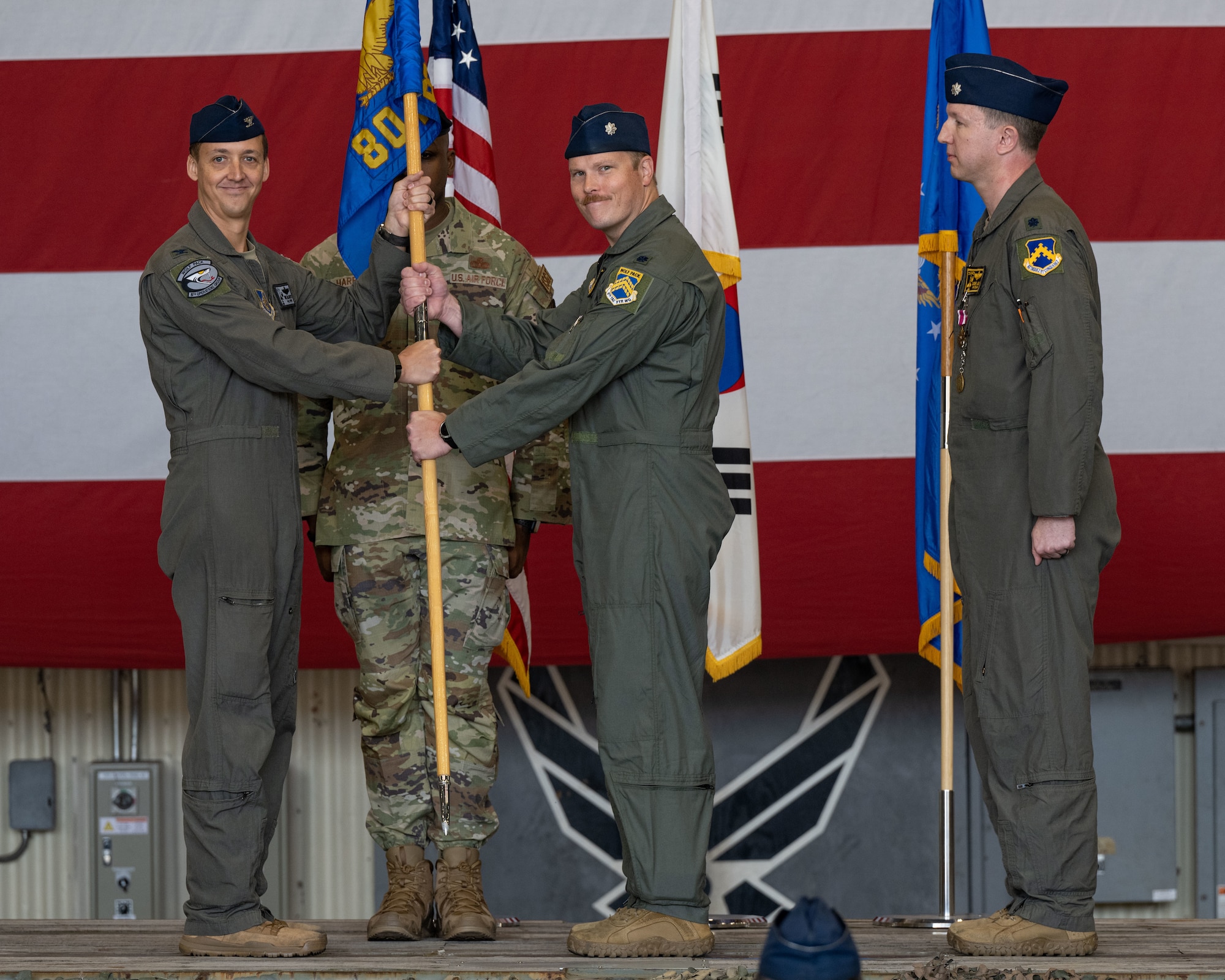 Col. Michael McCarthy, left, 8th Operations Group commander, passes the 80th Fighter Squadron guidon from Lt. Col. Dana Merril, right, 80th FS incoming commander, at the 80th FS change of command ceremony.