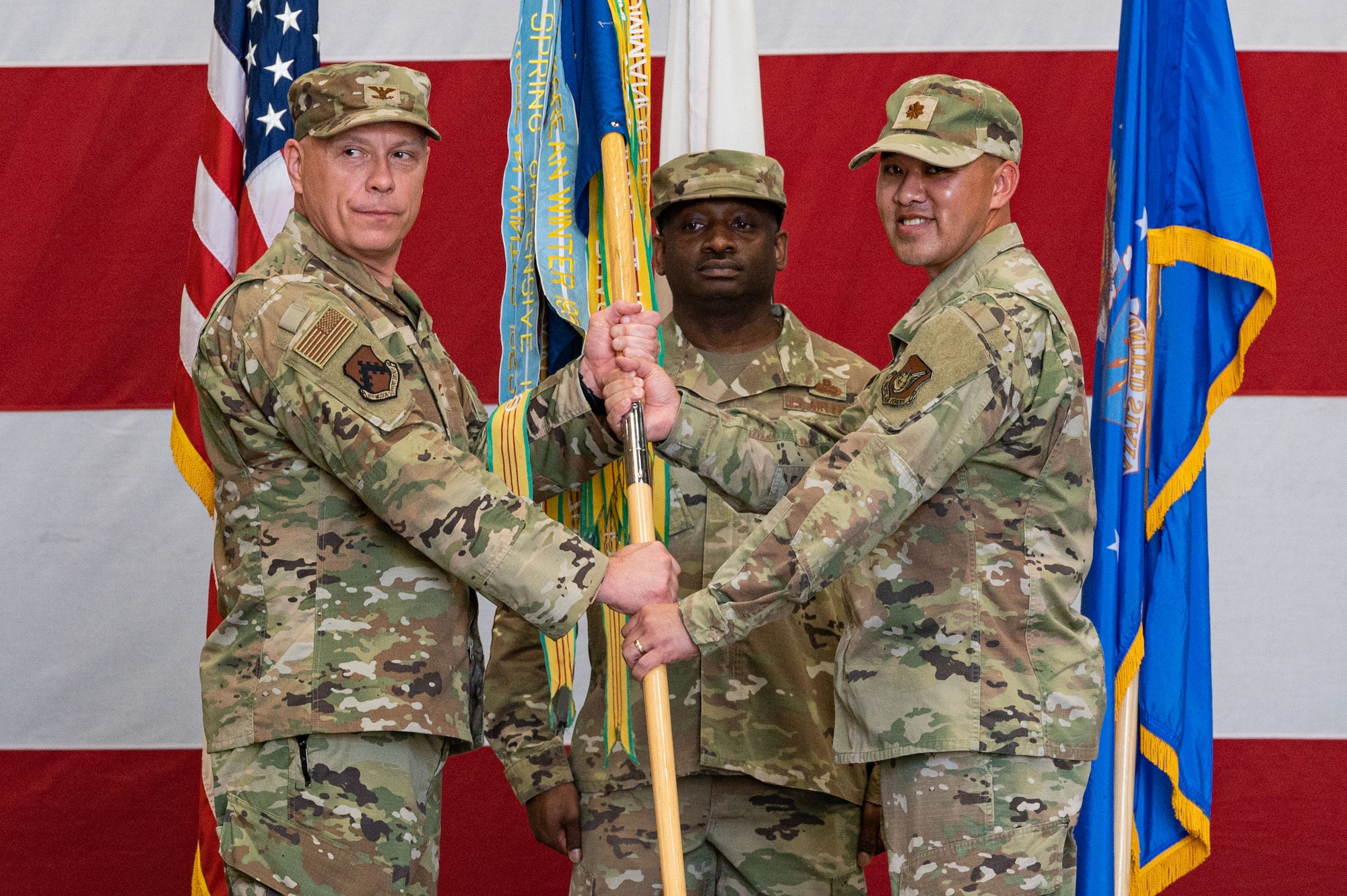 U.S. Air Force Col. Christopher Lacek, 8th Mission Support Squadron commander, passes the guidon to Maj. Tuan Vu, 8th Communications Squadron incoming commander, during the 8th CS change of command ceremony.