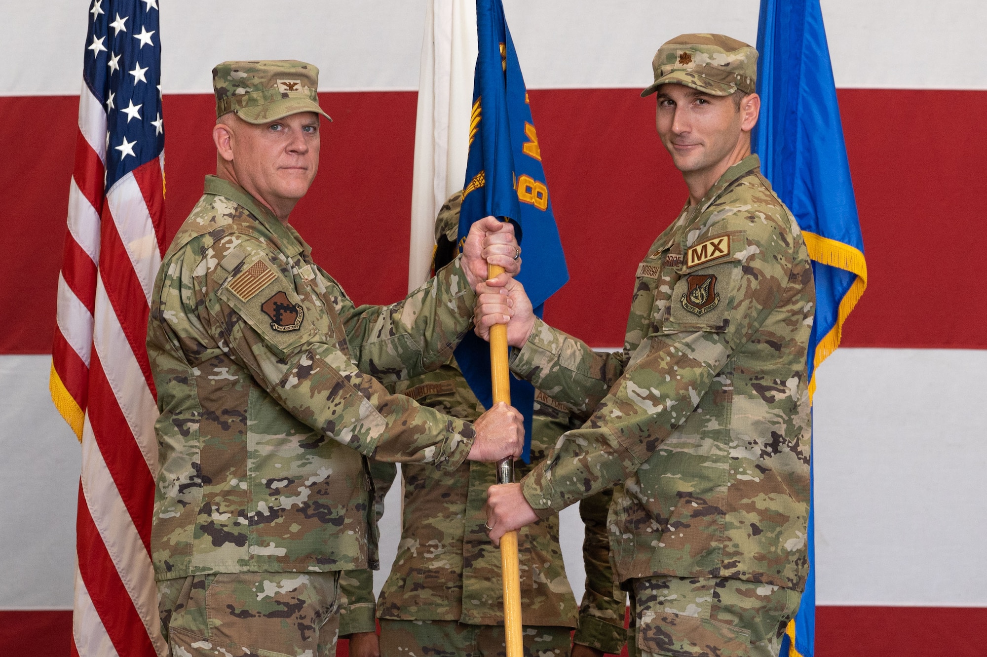 U.S. Air Force Col. Casey Crabill, left, 8th Maintenance Group commander, passes the guidon to Maj. Michael Parrish, 8th Maintenance Squadron incoming commander, during the 8th MXS change of command ceremony.