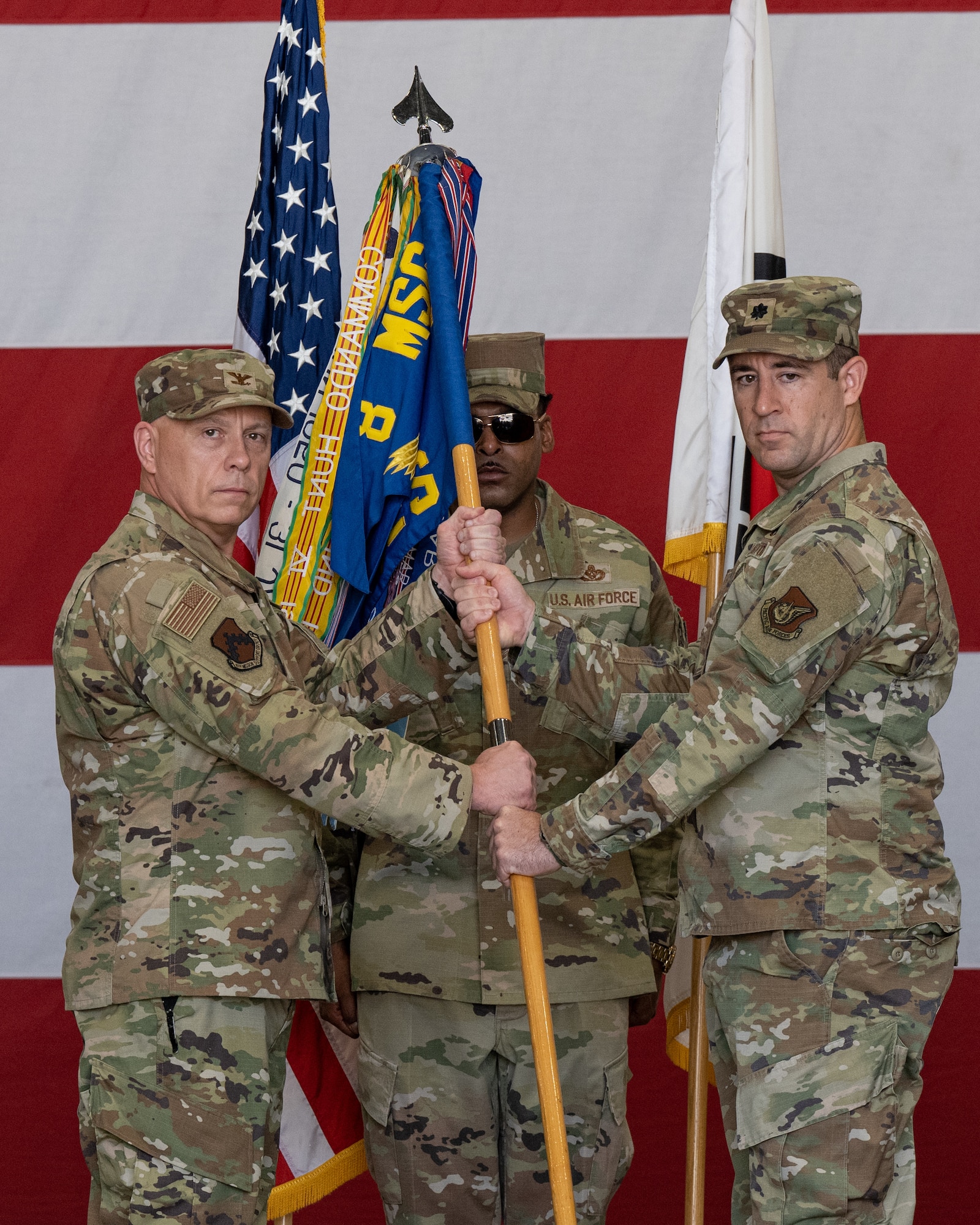 U.S. Air Force Col. Christopher Lacek, 8th Mission Support Group commander, passes the 8th Civil Engineer Squadron guidon to Lt. Col. Phil Compton, 8th CES incoming commander, during the 8th CES change of command ceremony.