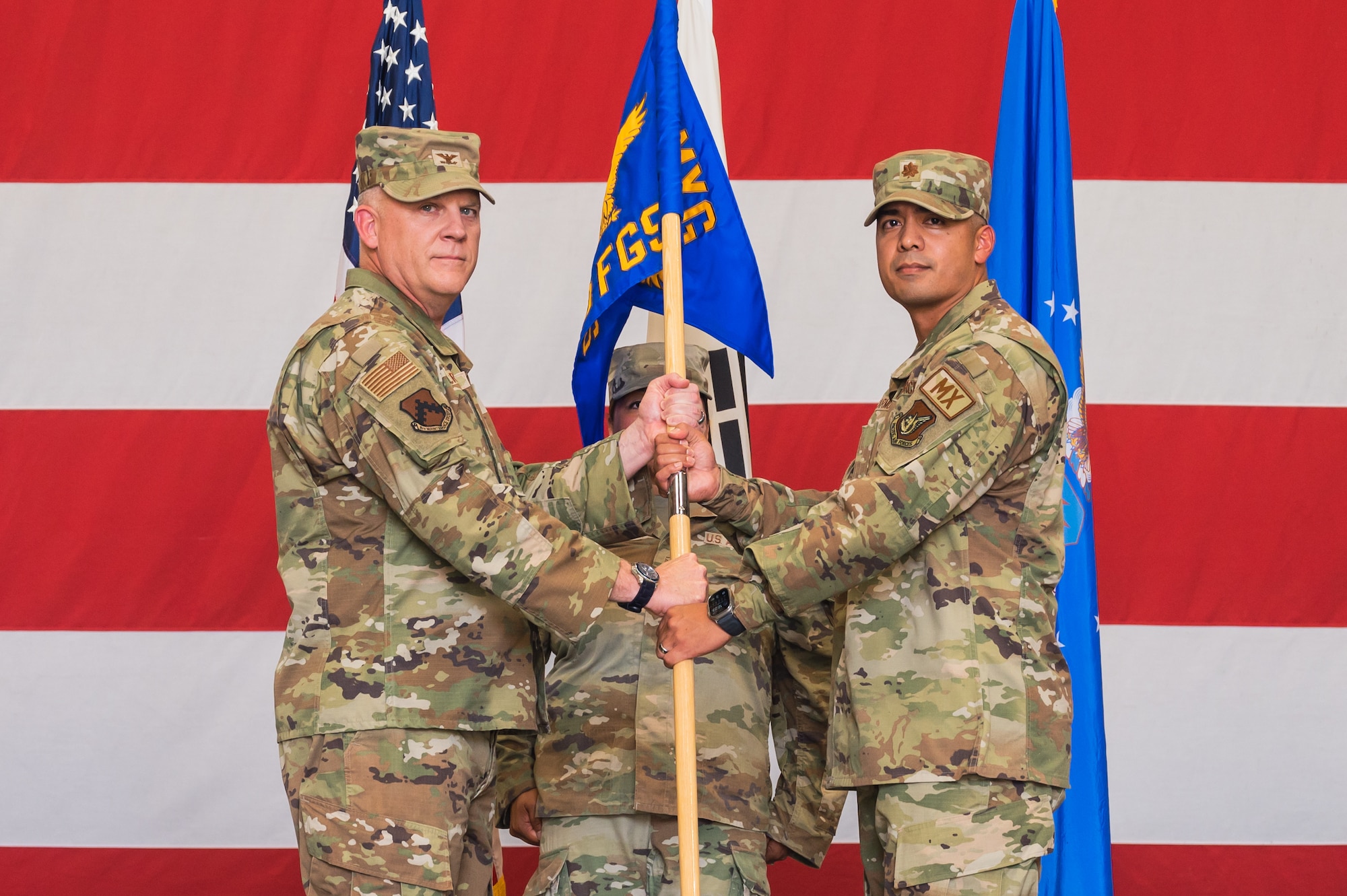 U.S. Air Force Col. Casey Crabill, 8th Maintenance Group commander, passes the guidon to Maj. Alex Carmona, 80th Fighter Generation Squadron incoming commander, during the 80th FGS change of command ceremony.