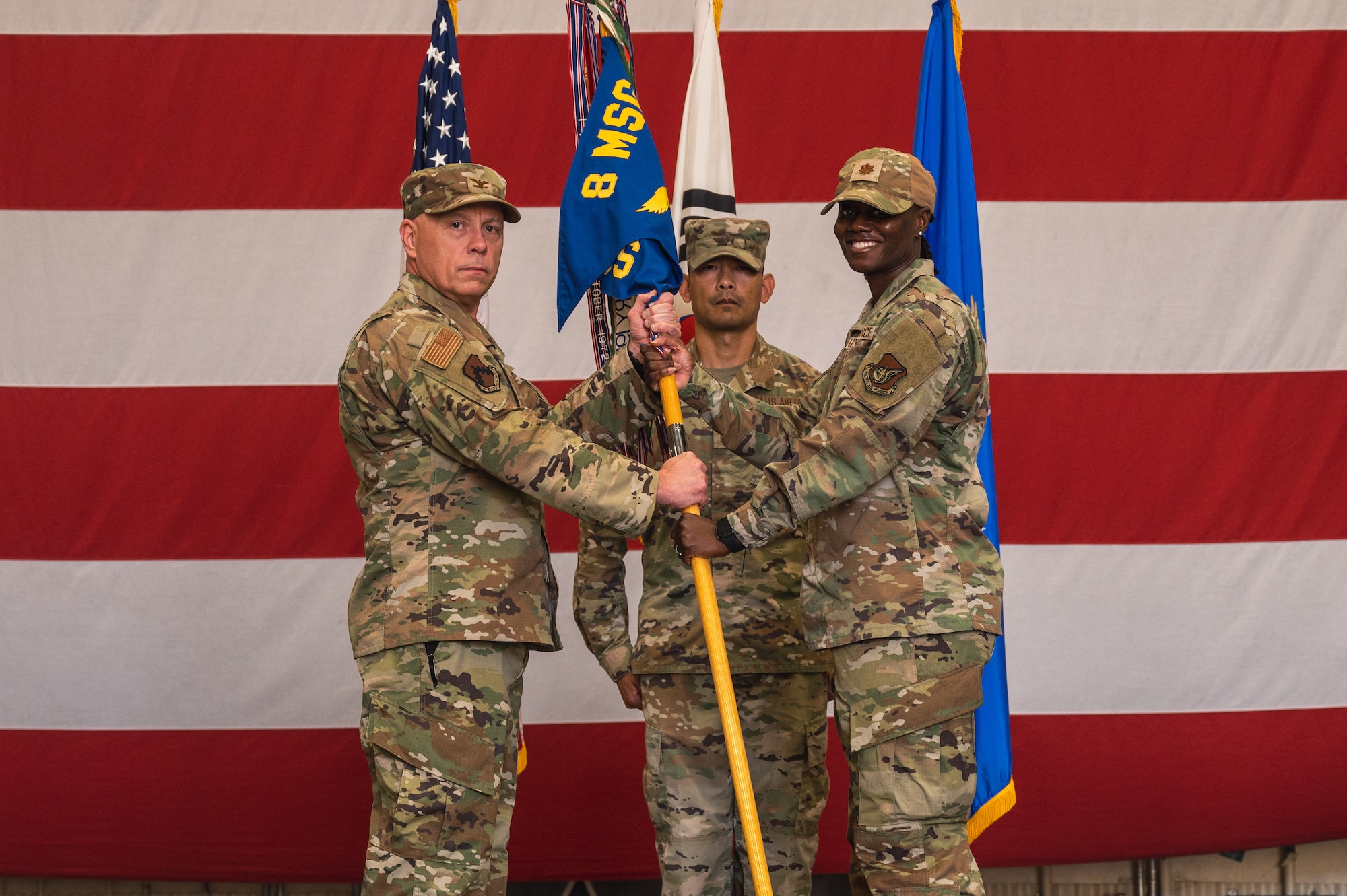U.S. Air Force Col. Christopher Lacek, 8th Mission Support Group commander, passes the guidon to Maj. Jamila Edgerson, 8th Force Support Squadron incoming commander, during the 8th FSS change of command ceremony.