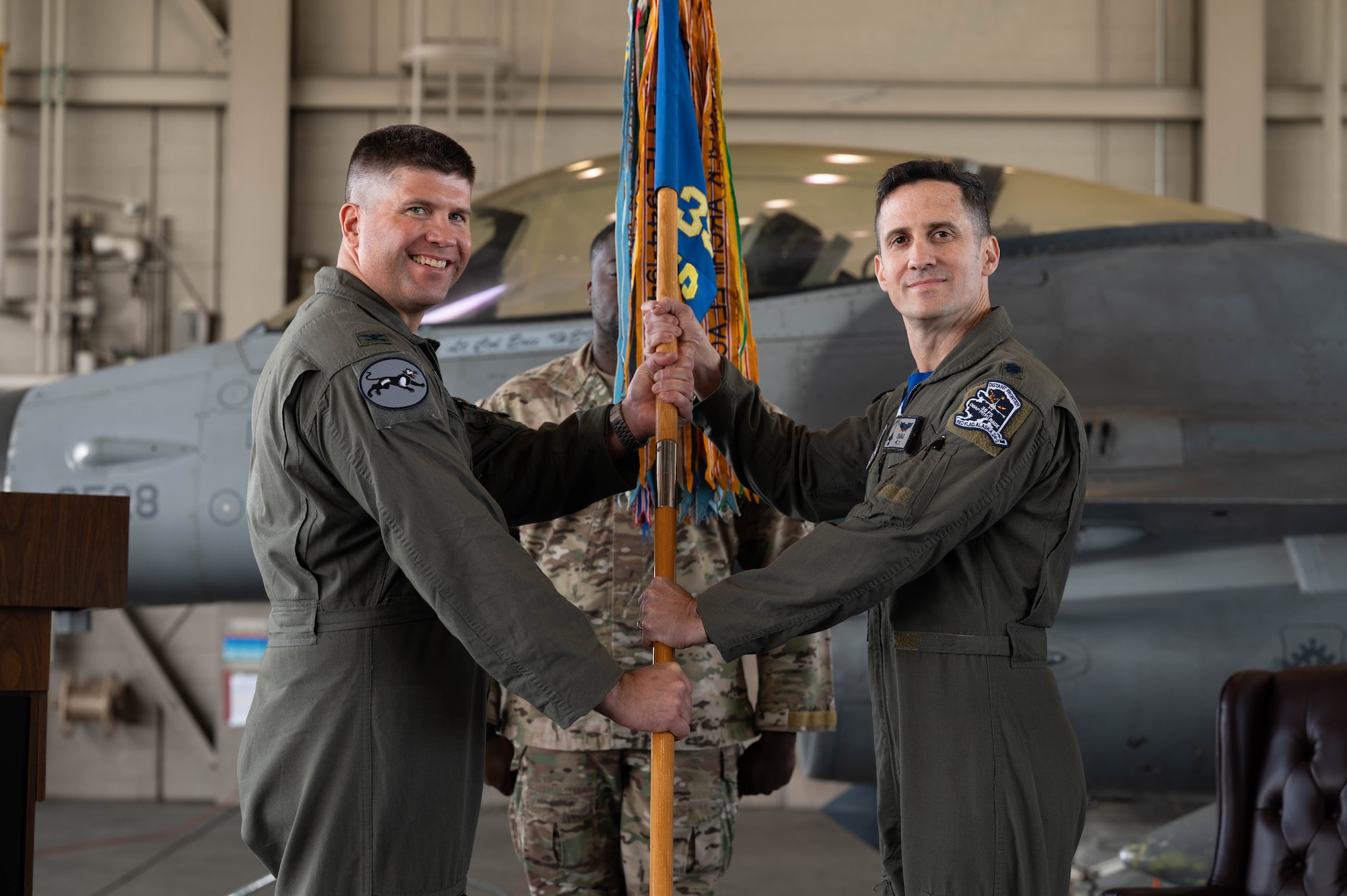 U.S. Air Force Col. Derrick Franck, 8th Operations Group commander, passes the guidon to Lt. Col. Sean Murphy, 35th Fighter Squadron incoming commander, during the 35th FS change of command ceremony.