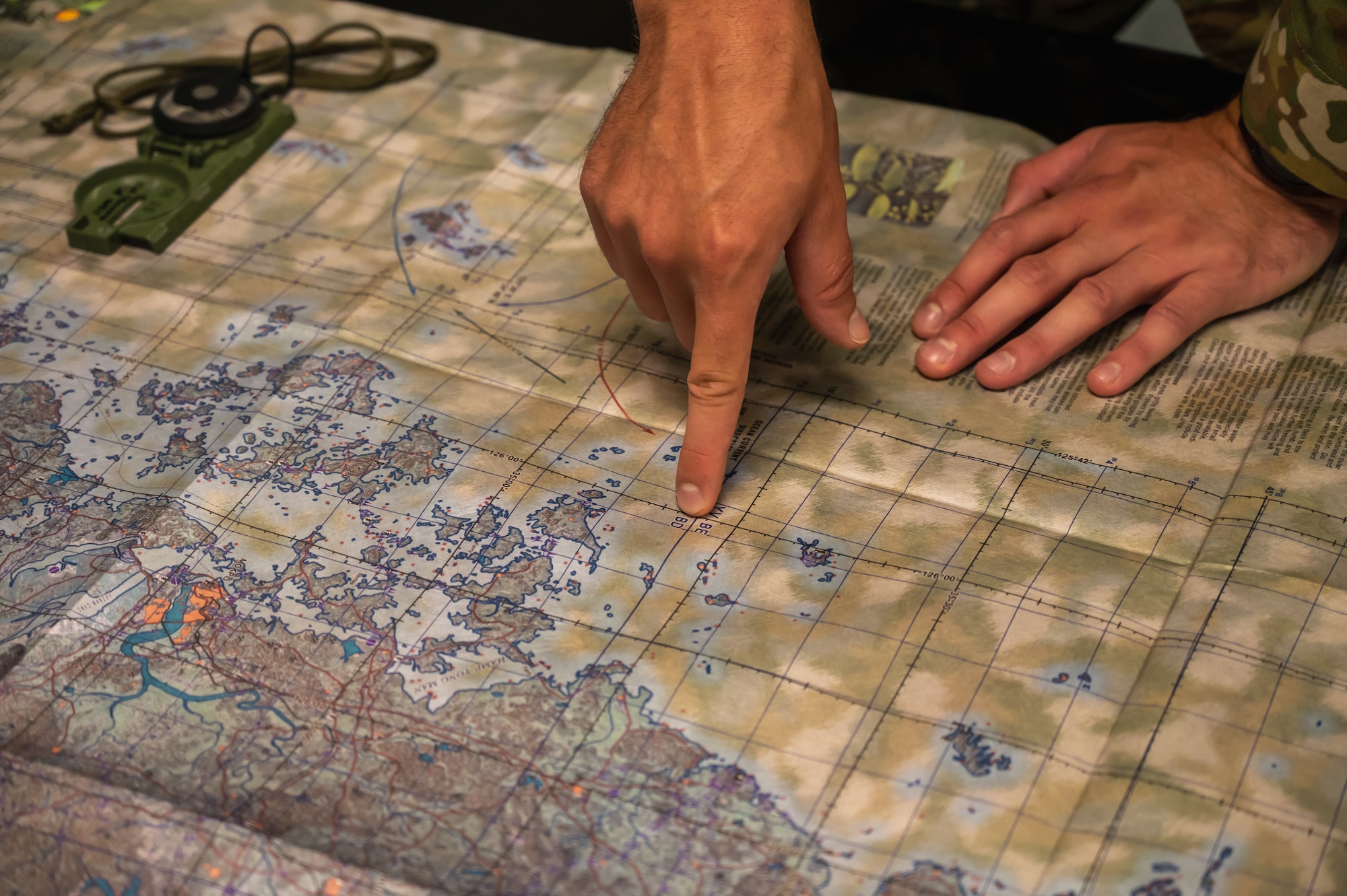 Senior Airman Devan Skeem, 8th Operations Support Squadron survival, evasion, resistance, and escape specialist, points at a location on a map.