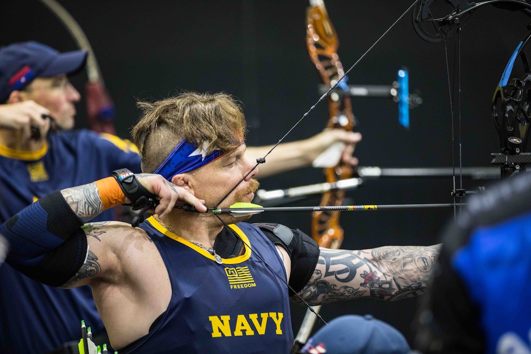 An athlete squints while preparing to shoot an arrow from a bow.