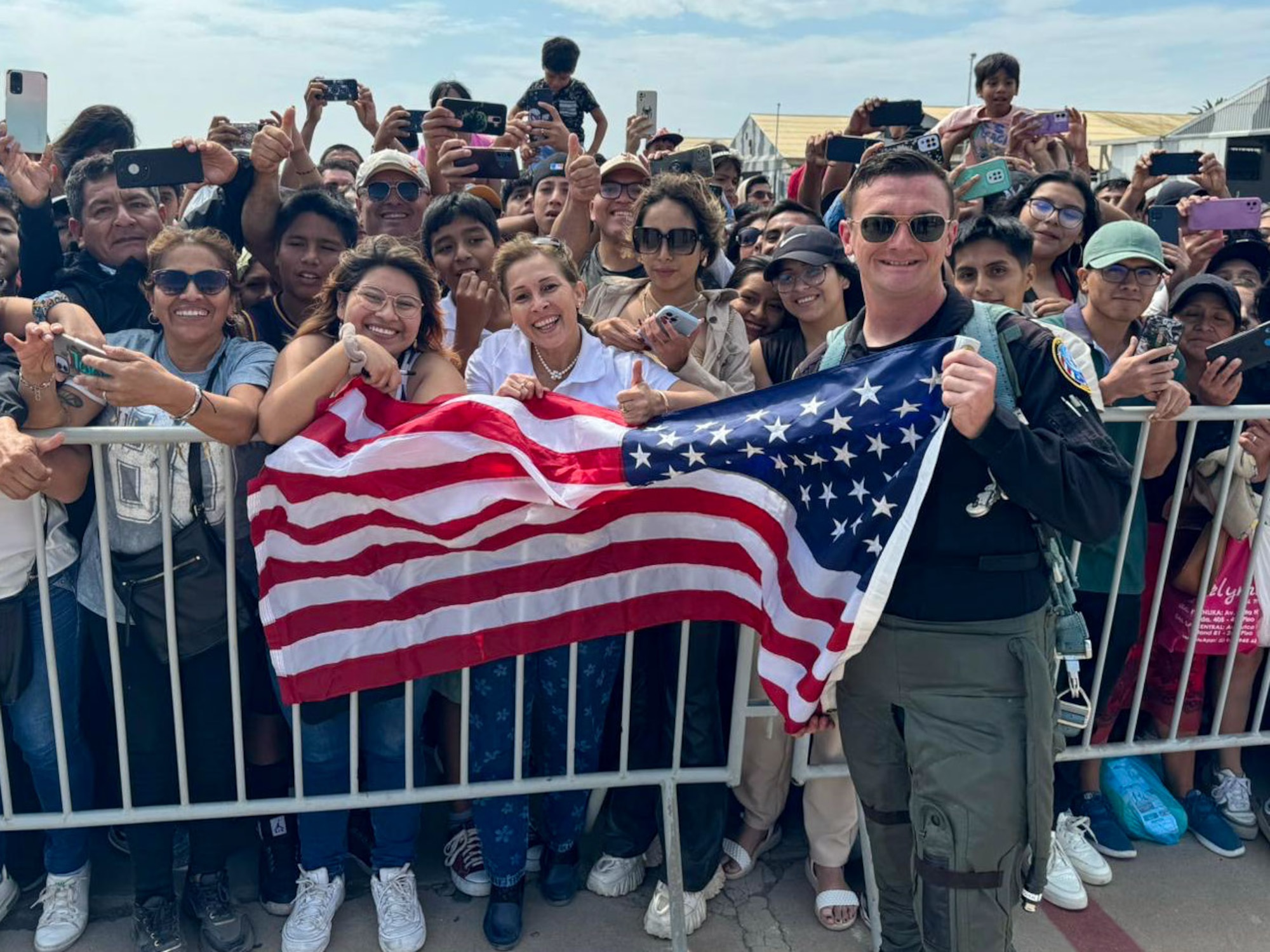 Captain Hiester holds an American flag for a photo with a group of spectators.