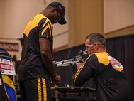 U.S. Army Staff Sgt. Derrick Thompson, left, assists Maj. Jeremy Ditlevson with loading his air rifle at the precision air event during the 2024 Department of Defense Warrior Games