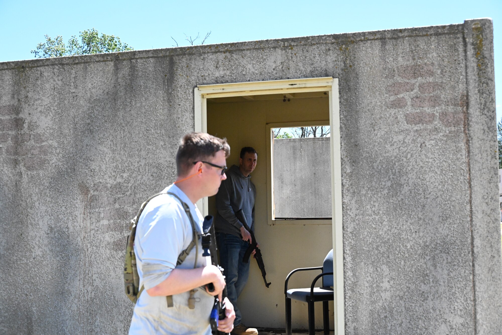Male walks by open door while carrying a simulated weapon.