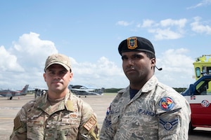 Fuerza Aérea de República Dominicana Cabo Zarzuela Cuevas, firefighter, right, and U.S. Air Force Tech. Sgt. Giancarlo Cintron, religious affairs noncommissioned officer, stand on the flight line at San Isidro Air Base, Dominican Republic, Feb. 16, 2023. These members are preparing for exercise Forward Tiger was designed to build on longstanding partnerships throughout the Caribbean and contribute to enhanced military readiness, humanitarian relief, and disaster response capabilities. (U.S. Air Force photo by 1st Lt. Christian Little)