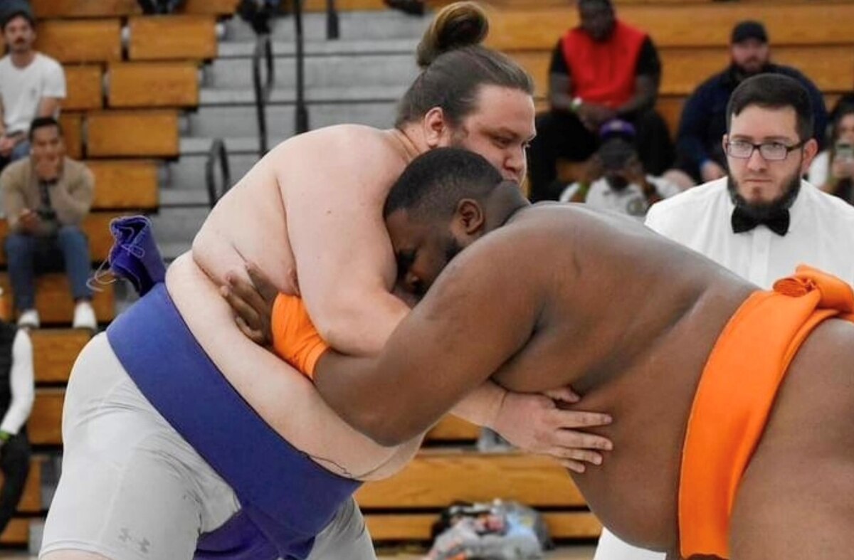 close up of competitors grappling with each other while the referee looks on.
