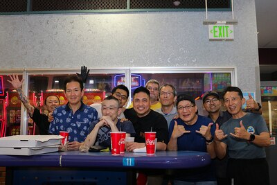 A group of 10 people pose for a group photo behind a table in a bowling alley.