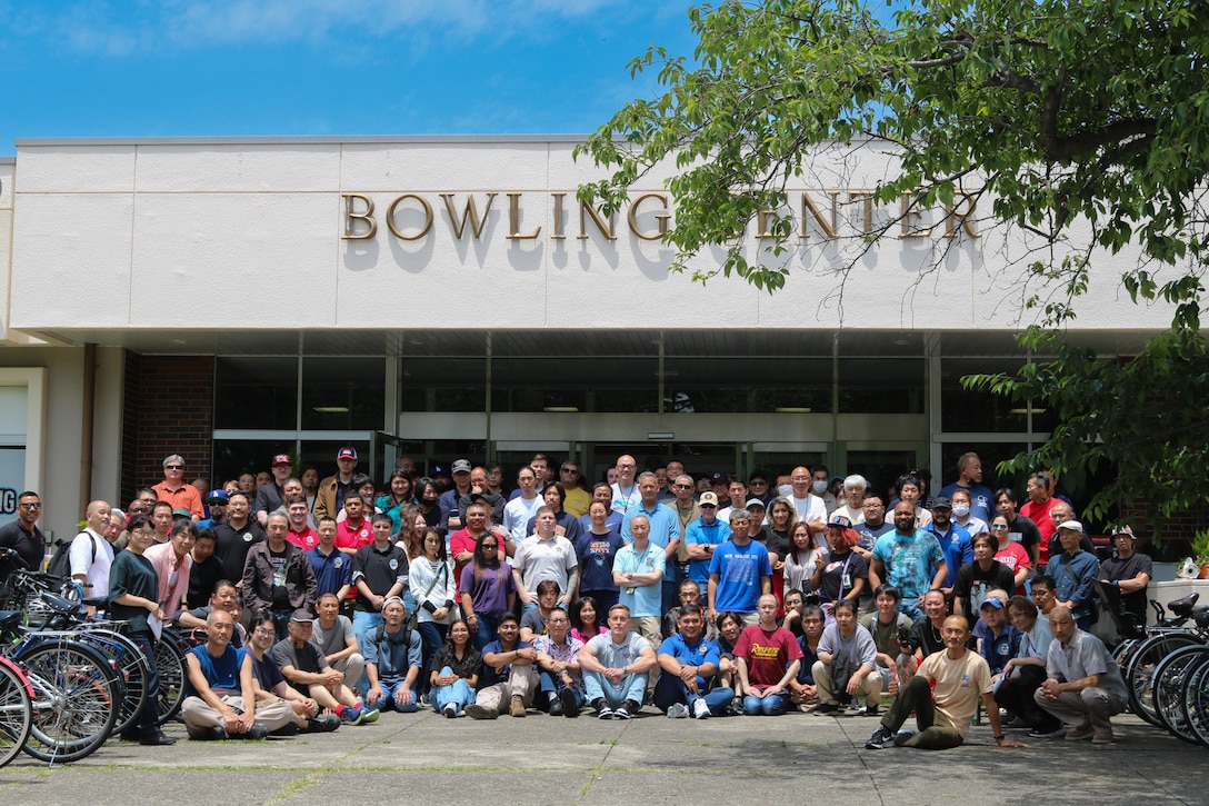 A group of people pose outside of a building that is labeled 'Bowling Center'.