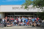 A group of people pose outside of a building that is labeled 'Bowling Center'.