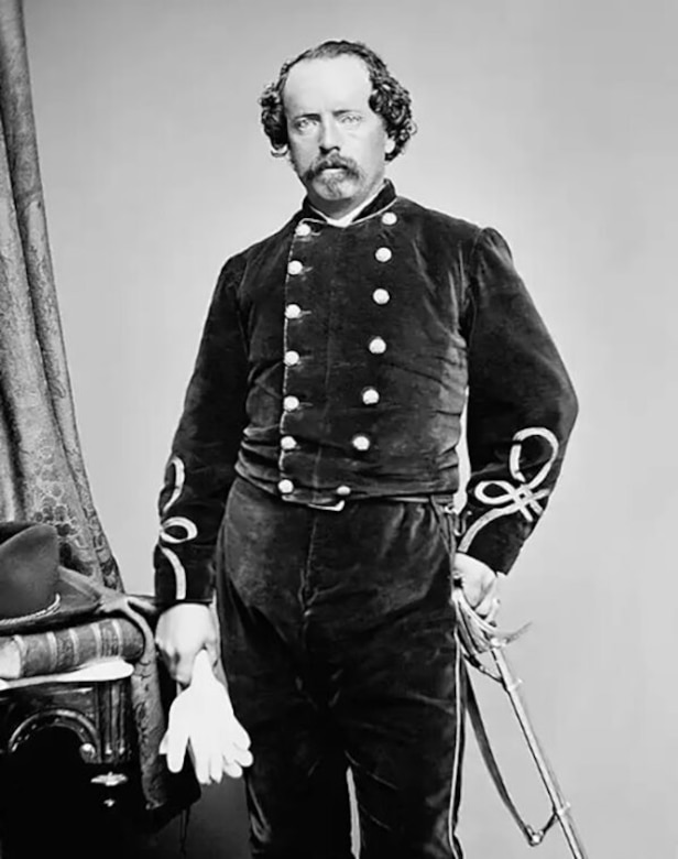 A man in uniform and holding white gloves poses for a photo.