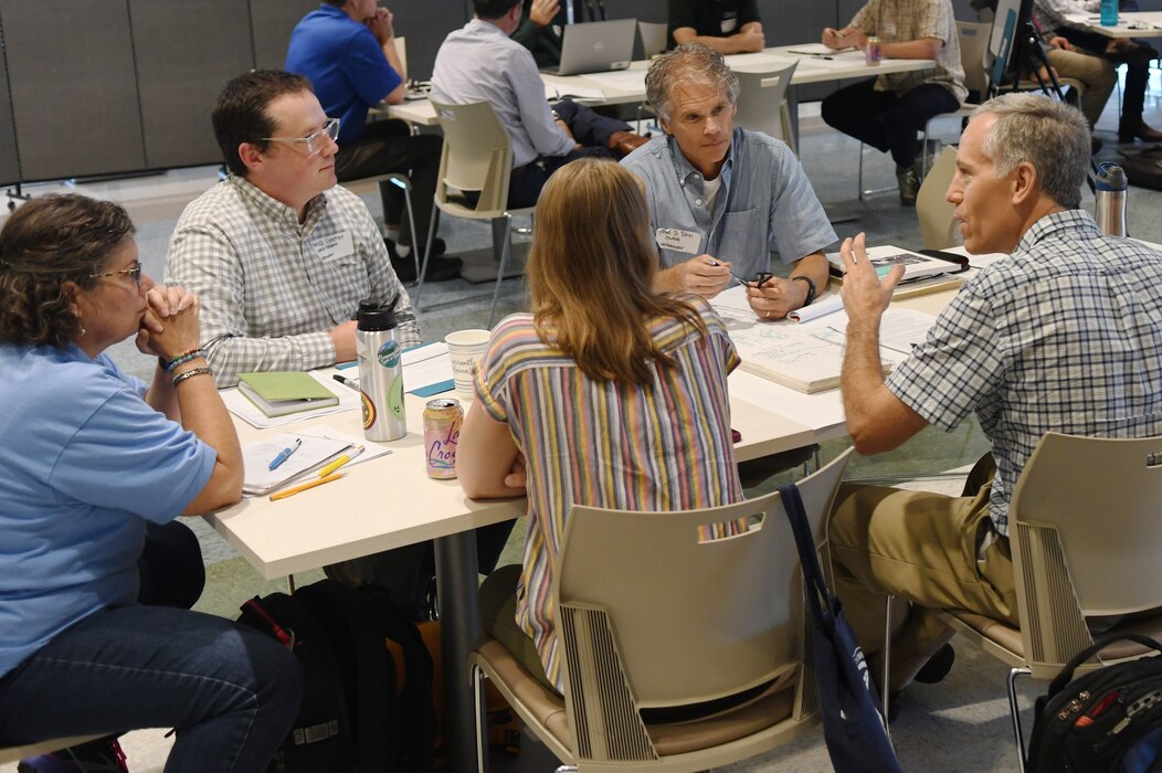 A team of experts participate in a discussion around a table.