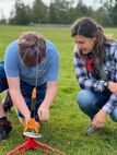 Elissa Forsman (right), a Strategic Weapons Facility-Pacific (SWFPAC) Science, Technology, Engineering, and Math (STEM) volunteer from Bangor, Washington oversees a student from Ridgetop Middle school while he connects the launch controller to a rocket fuse. SWFPAC’s STEM program has supported four successful launches from 2023-2024, and volunteers ensure the safety of students during the rocket launches; assist with connecting launchers; fix faulty fuses; and answer questions about how rocket launches relate to SWFPAC’s real-world mission. SWPFAC is the command dedicated to assembling, maintaining, and storing TRIDENT II D5 Missiles and deploying them on fleet ballistic missile submarines (U.S. Navy Photo by Chani Wenning/Released)