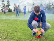 Andrew Samuelson a Strategic Weapons Facility-Pacific (SWFPAC) Science, Technology, Engineering, and Math (STEM) volunteer, prepares a test rocket for launch during an event with Ridgetop Middle School in early June. SWFPAC’s STEM program has supported four successful launches from 2023-2024, and volunteers ensure the safety of students during the rocket launches; assist with connecting launchers; fix faulty fuses; and answer questions about how rocket launches relate to SWFPAC’s real-world mission. SWPFAC is the command dedicated to assembling, maintaining, and storing TRIDENT II D5 Missiles and deploying them on fleet ballistic missile submarines (U.S. Navy Photo by Chani Wenning/Released)
